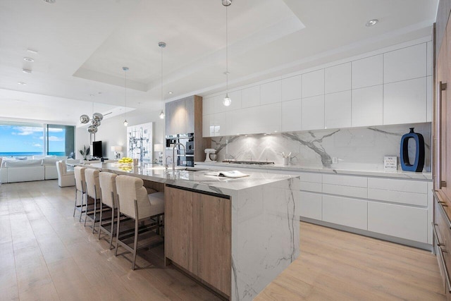 kitchen featuring a large island, white cabinets, and a raised ceiling