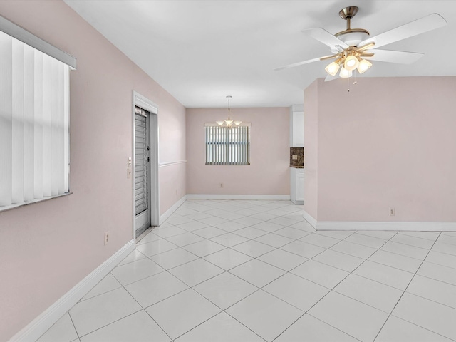 unfurnished room with ceiling fan with notable chandelier and light tile patterned floors