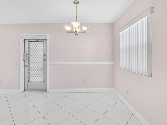 spare room with light tile patterned floors and an inviting chandelier