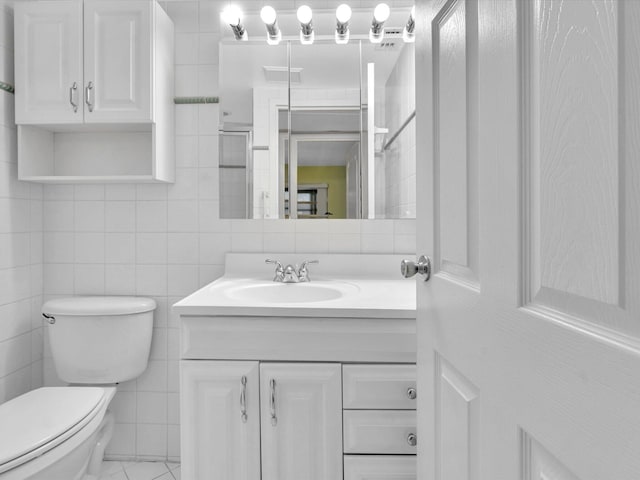 bathroom with vanity, a shower with door, toilet, and tile walls