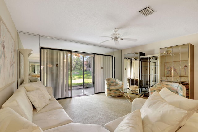 living room with ceiling fan, carpet floors, and a textured ceiling