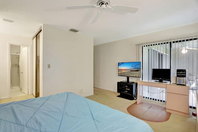 carpeted bedroom with ceiling fan, a closet, ensuite bathroom, and a textured ceiling