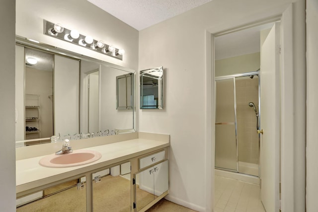 bathroom featuring vanity, a textured ceiling, a shower with door, and tile patterned flooring