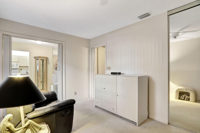 sitting room featuring light colored carpet and ceiling fan