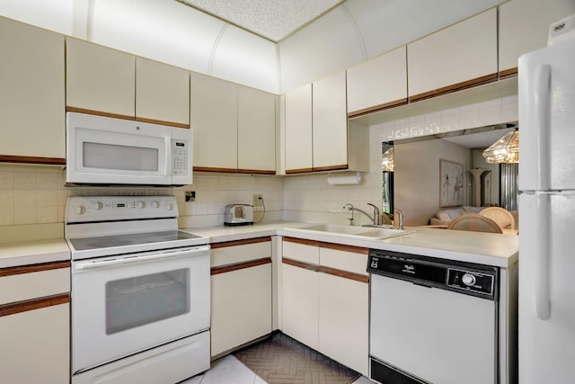 kitchen with white cabinetry, sink, backsplash, kitchen peninsula, and white appliances