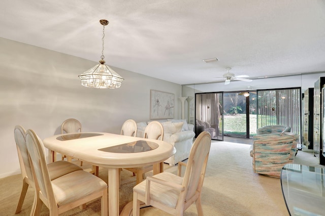 carpeted dining area with ceiling fan with notable chandelier and expansive windows