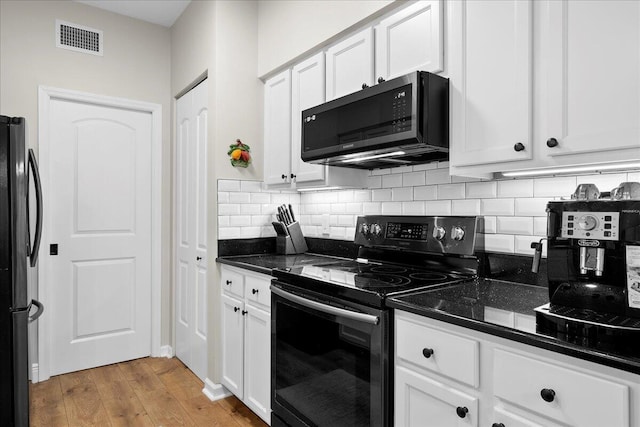 kitchen featuring electric range, dark stone countertops, fridge, white cabinets, and light wood-type flooring