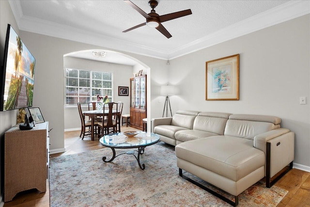 living room featuring a textured ceiling, light hardwood / wood-style flooring, ceiling fan, and crown molding