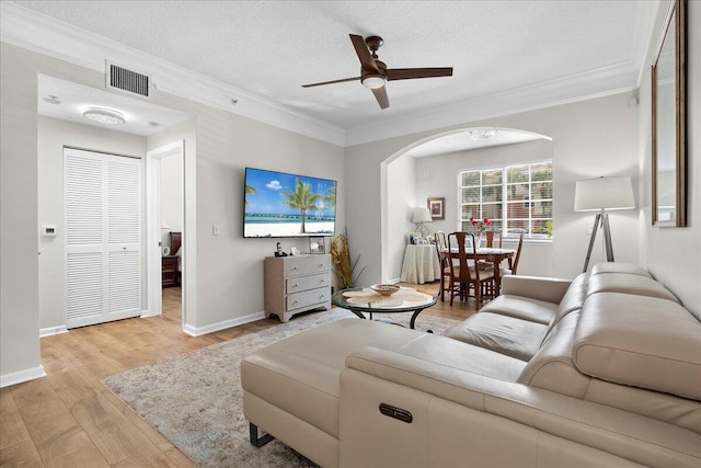 living room featuring ceiling fan, light hardwood / wood-style flooring, a textured ceiling, and ornamental molding