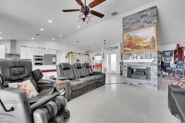 living room featuring a textured ceiling, vaulted ceiling, ceiling fan, and a stone fireplace