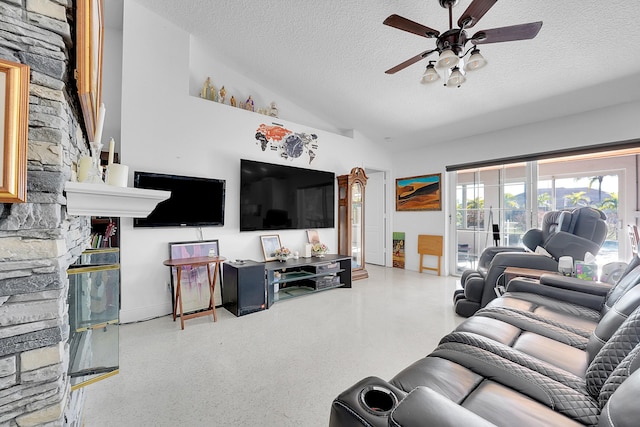 living room with vaulted ceiling, ceiling fan, a fireplace, and a textured ceiling