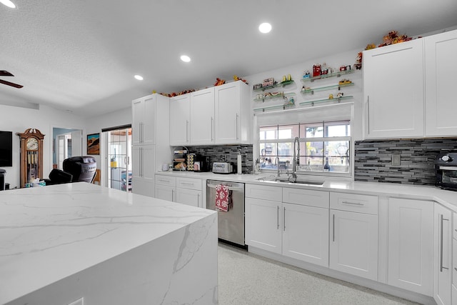 kitchen featuring light stone counters, sink, white cabinets, and stainless steel dishwasher