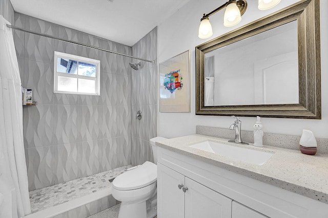 bathroom with vanity, toilet, and tiled shower