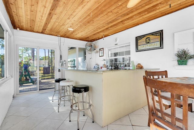 kitchen with light stone counters, hanging light fixtures, light tile patterned floors, and wood ceiling