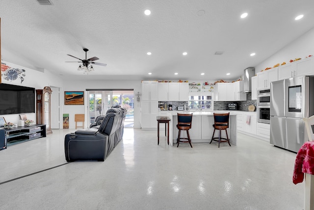 living room with a textured ceiling, ceiling fan, and sink