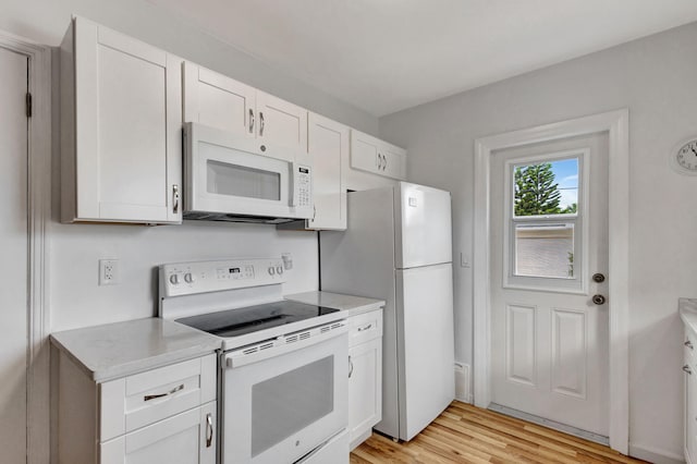 kitchen with white cabinets, light hardwood / wood-style floors, and white appliances