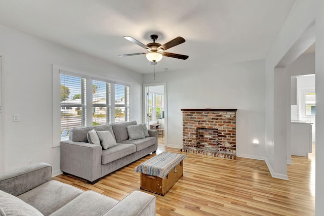 living room featuring ceiling fan, a fireplace, and light hardwood / wood-style floors