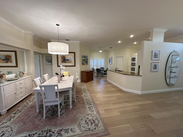 dining area with light hardwood / wood-style flooring, crown molding, and sink