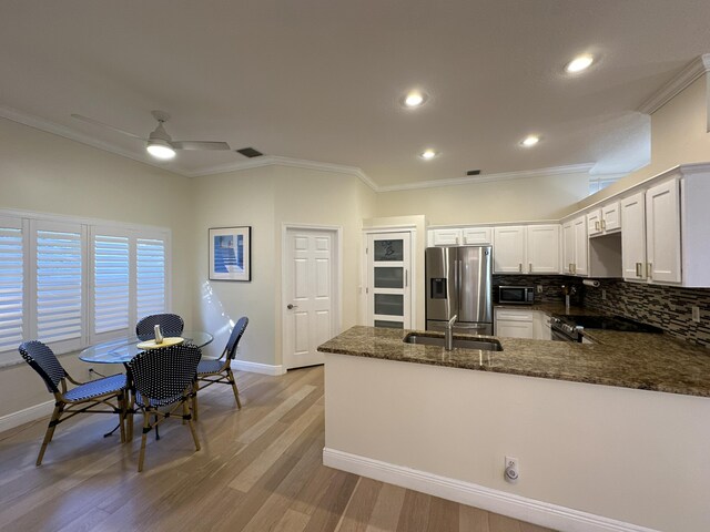 kitchen with stainless steel fridge with ice dispenser, ornamental molding, and light hardwood / wood-style flooring