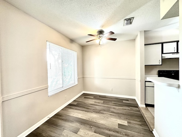 unfurnished dining area with ceiling fan, dark wood-type flooring, and a textured ceiling