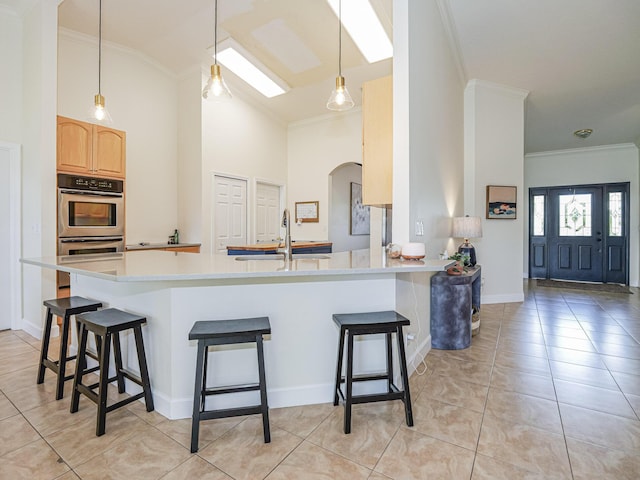 kitchen with kitchen peninsula, light brown cabinetry, sink, light tile patterned floors, and a breakfast bar area