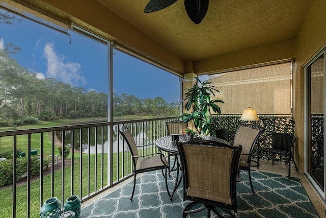 sunroom featuring a water view and a ceiling fan