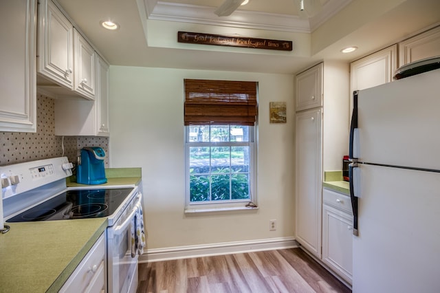 kitchen featuring a raised ceiling, white fridge, electric range oven, and white cabinetry