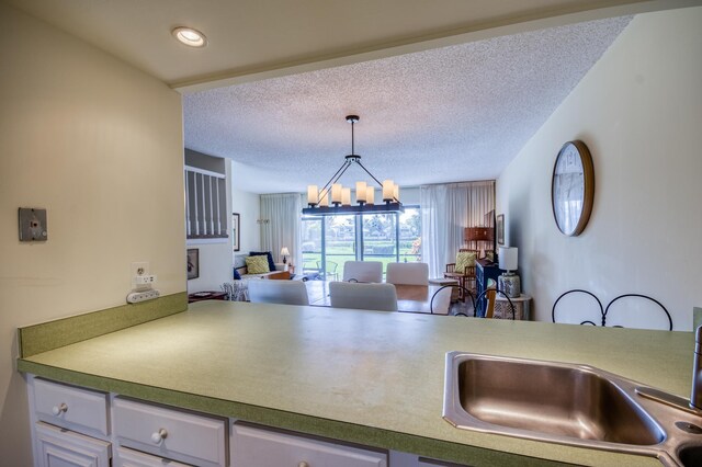 kitchen featuring a chandelier, a textured ceiling, decorative light fixtures, and sink