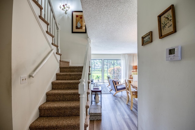 staircase featuring a textured ceiling and hardwood / wood-style flooring