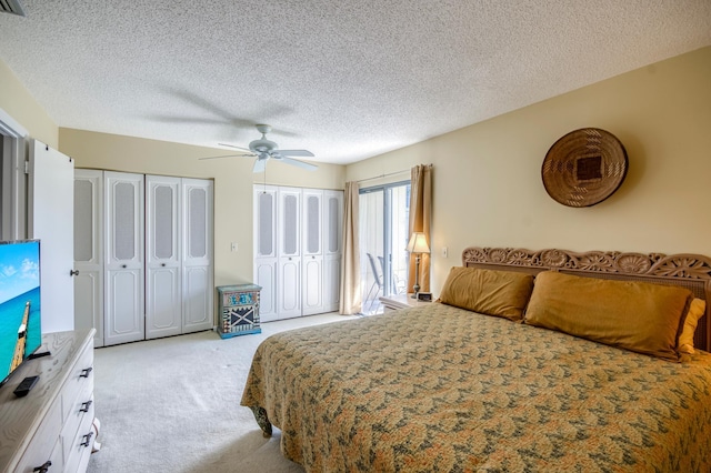 carpeted bedroom featuring multiple closets, ceiling fan, and a textured ceiling