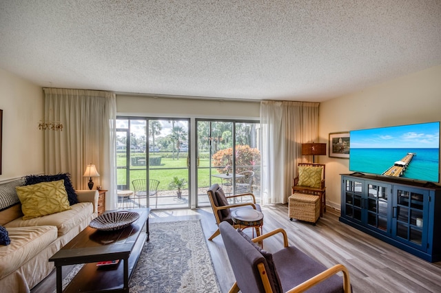 living room with plenty of natural light, a textured ceiling, and light hardwood / wood-style flooring