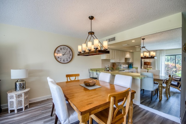 dining space featuring a textured ceiling, dark hardwood / wood-style flooring, a notable chandelier, and sink