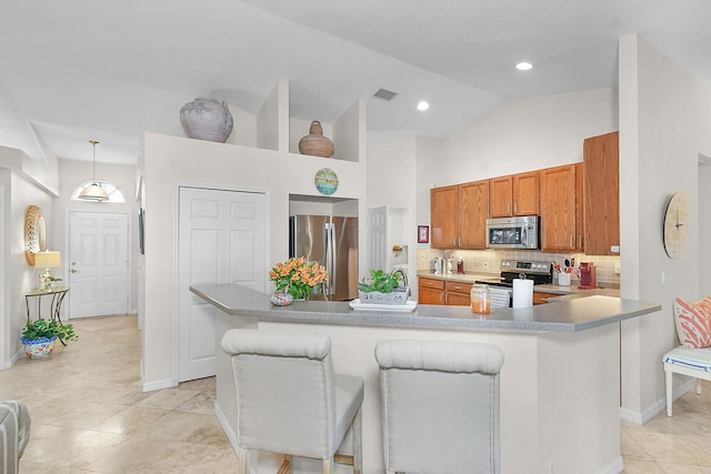 kitchen featuring stainless steel appliances, decorative backsplash, a kitchen bar, decorative light fixtures, and kitchen peninsula