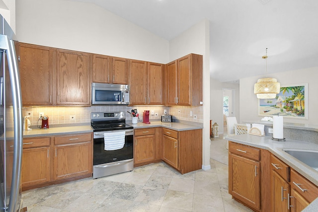 kitchen featuring lofted ceiling, sink, tasteful backsplash, decorative light fixtures, and appliances with stainless steel finishes