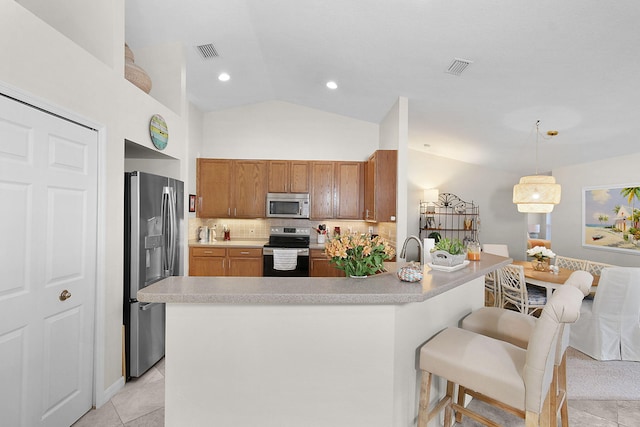 kitchen with vaulted ceiling, appliances with stainless steel finishes, light tile patterned flooring, tasteful backsplash, and hanging light fixtures