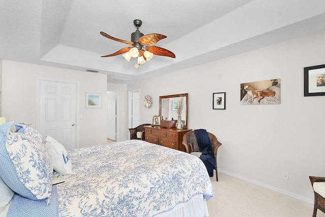 bedroom with a textured ceiling, a raised ceiling, and ceiling fan