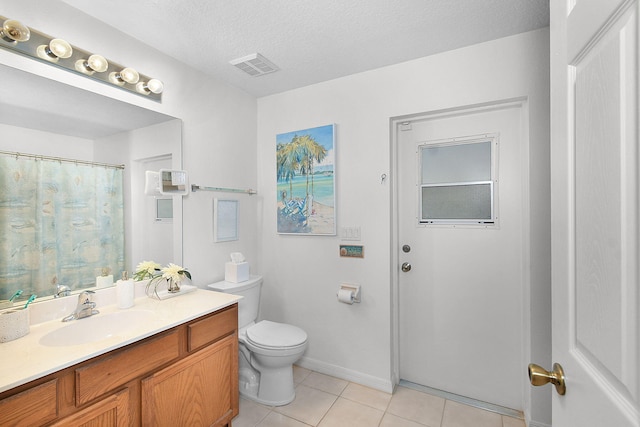 bathroom featuring vanity, toilet, tile patterned flooring, and a textured ceiling