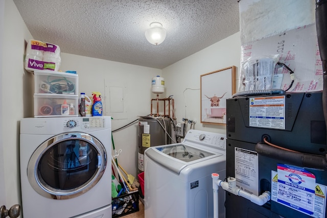 laundry room with washing machine and dryer, water heater, and a textured ceiling