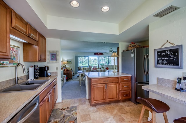 kitchen with sink, kitchen peninsula, stainless steel appliances, and a tray ceiling