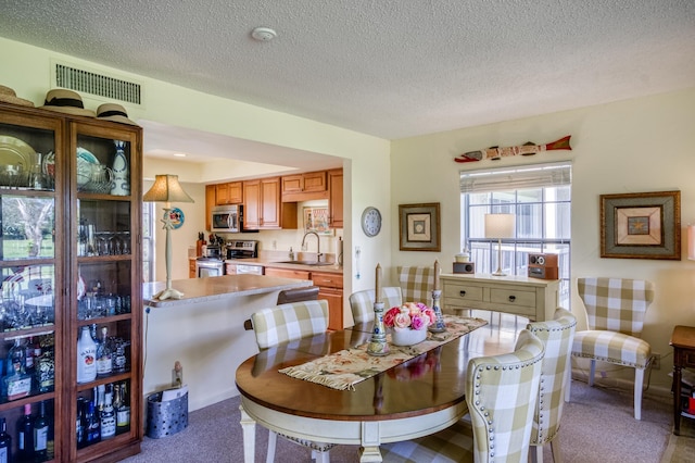 carpeted dining area with sink and a textured ceiling