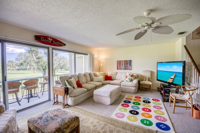 living room featuring ceiling fan, light colored carpet, and a textured ceiling