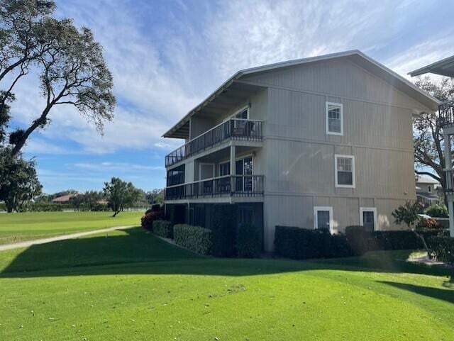 view of side of property featuring a yard and a balcony