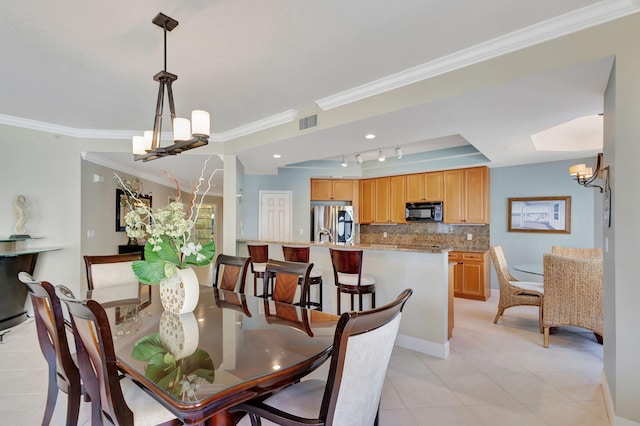 tiled dining area with crown molding, rail lighting, and a chandelier