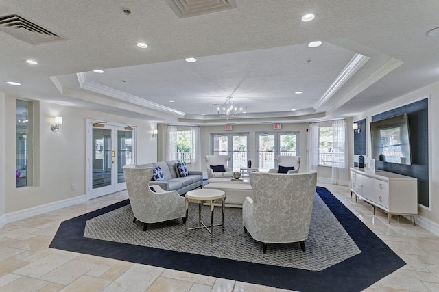 living room featuring an inviting chandelier, french doors, crown molding, and a tray ceiling