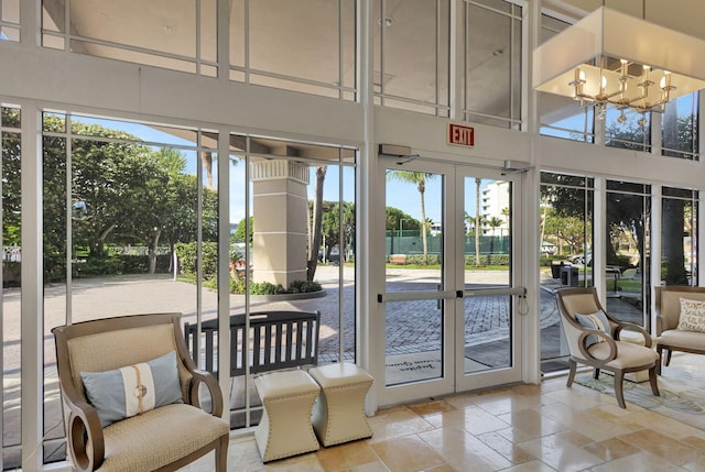 doorway to outside with french doors, an inviting chandelier, and a high ceiling