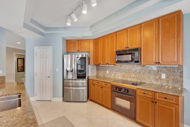 kitchen with light stone counters, a tray ceiling, sink, black appliances, and light tile patterned flooring