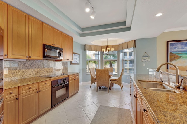 kitchen featuring black appliances, a raised ceiling, sink, hanging light fixtures, and a notable chandelier