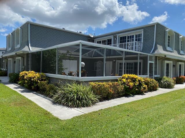 back of house with glass enclosure and a yard