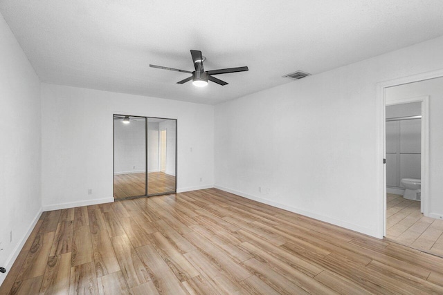 1701 Vision Dr, Palm Beach Gardens, FL 33418 - unfurnished bedroom featuring light wood finished floors, a closet, baseboards, ceiling fan, and ensuite bath