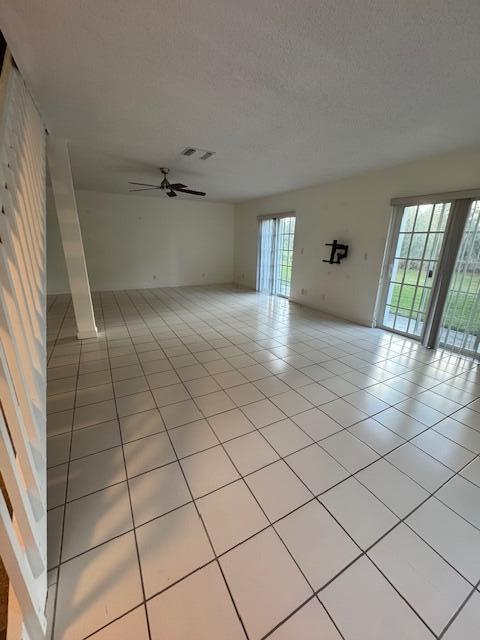 tiled spare room with a textured ceiling and ceiling fan